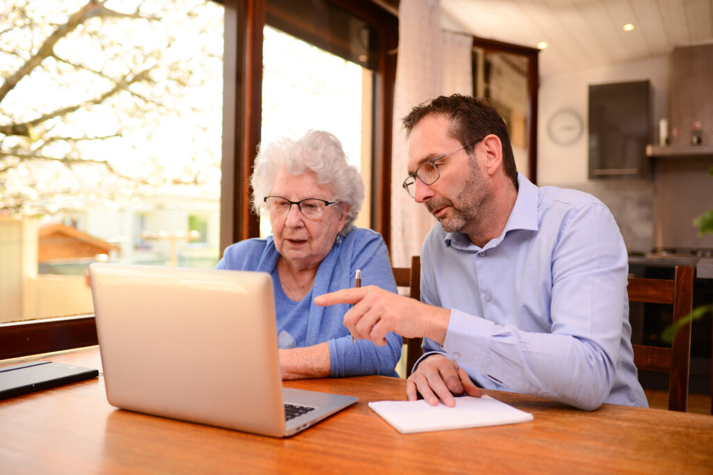 middle aged man assisting senior woman on a laptop computer